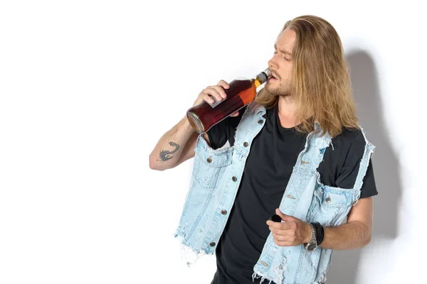 Schöner junger Mann in Jeansweste trinkt Rum auf Weiß — Stockfoto
