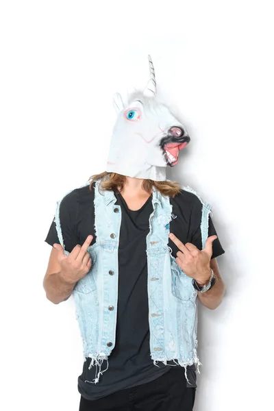 Homme en masque de licorne et gilet en denim montrant les doigts du milieu sur blanc — Photo de stock