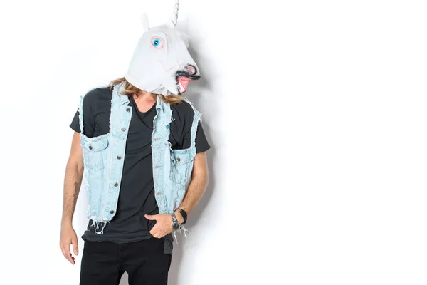 Homme en masque de licorne et gilet en denim debout sur blanc — Photo de stock