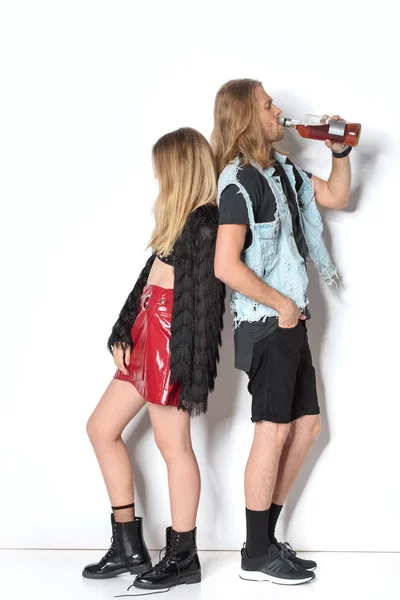 Side view of young addicted couple with bottle of rum on white — Stock Photo