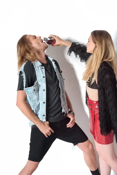 Jovem mulher derramando rum na boca do namorado no branco — Stock Photo