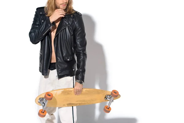 Beau jeune homme en veste en cuir avec longboard sur blanc — Photo de stock