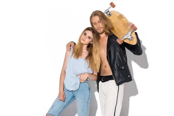 Stylish young couple with skateboard embracing on white — Stock Photo