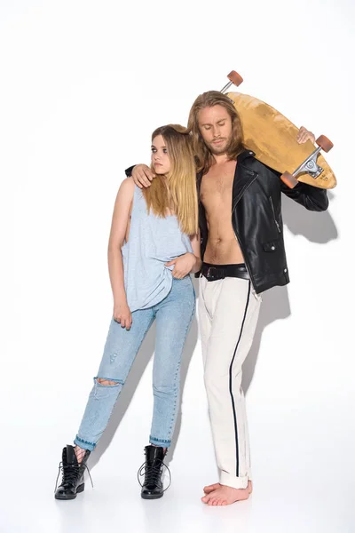 Fashionable young couple with skateboard embracing on white — Stock Photo