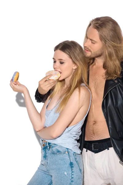 Élégant jeune couple manger des beignets savoureux sur blanc — Photo de stock
