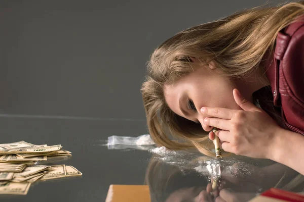 Side view of addicted young woman sniffing cocaine from glass table — Stock Photo