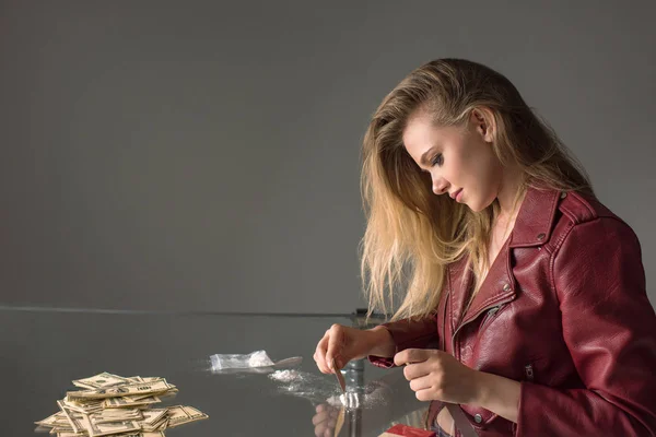 Vue latérale d'une jeune femme accro à la cocaïne sur une table en verre — Photo de stock
