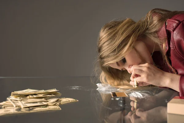 Seitenansicht einer jungen Junkie-Frau, die Kokain vom Glastisch schnuppert — Stockfoto