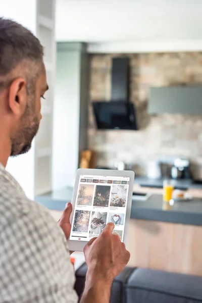 Selective focus of man using digital tablet with pinterest website on screen in kitchen — Stock Photo