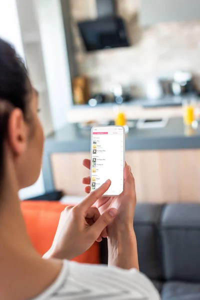 Selective focus of woman using smartphone in kitchen — Stock Photo