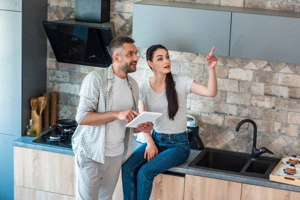 Casal com tablet digital olhando para longe na cozinha, conceito de casa inteligente — Fotografia de Stock