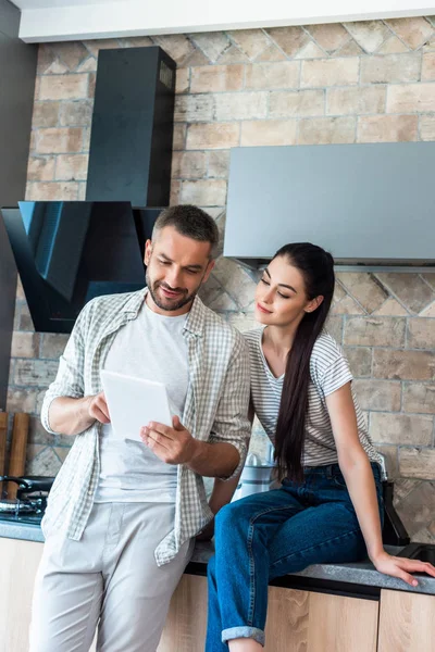 Portrait of smiling couple using digital tablet together in kitchen, smart home concept — Stock Photo