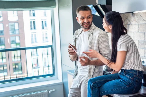 Side view of married couple using digital tablet together in kitchen, smart home concept — Stock Photo