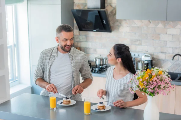 Retrato de pareja casada desayunando juntos en la cocina - foto de stock
