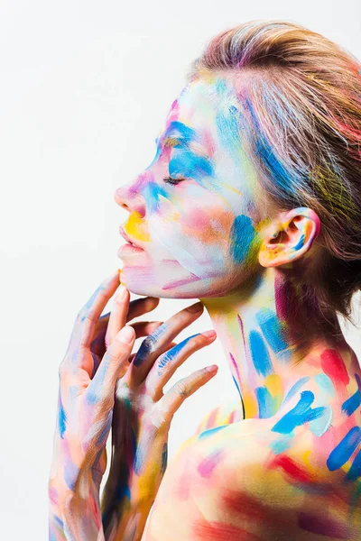 Vue latérale de la fille attrayante avec coloré lumineux corps art toucher menton isolé sur blanc — Photo de stock