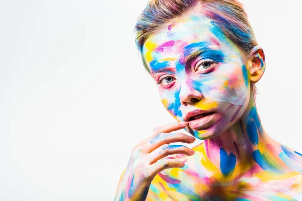 Atractiva chica con colorido brillante cuerpo arte tocando labio aislado en blanco - foto de stock