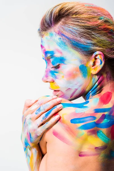 Chica atractiva con colorido arte del cuerpo brillante tocando hombro aislado en blanco - foto de stock