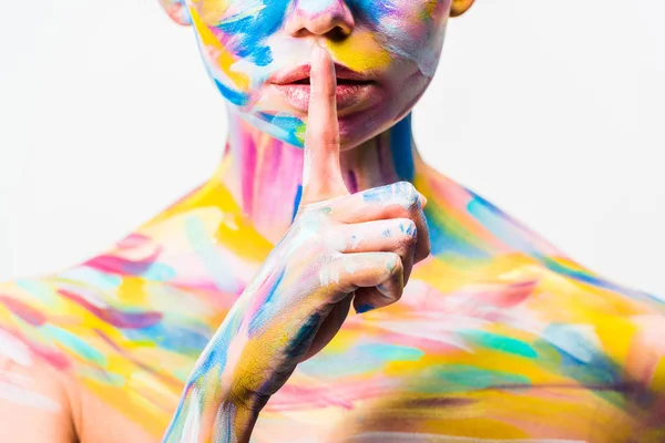 Imagem cortada de menina com arte corporal brilhante colorido mostrando gesto de silêncio isolado no branco — Fotografia de Stock