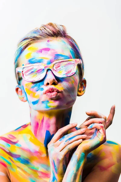 Menina atraente com arte corporal brilhante colorido e óculos de sol enviando beijo de ar isolado no branco — Fotografia de Stock