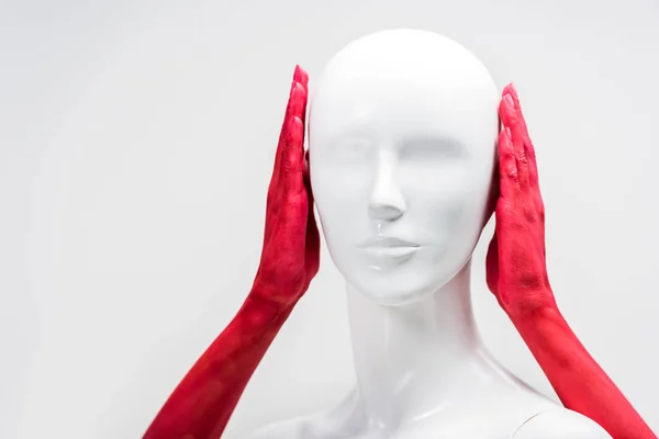 Обрізане зображення жінки в червоній фарбі, що покриває вуха манекена ізольовані на білому — стокове фото