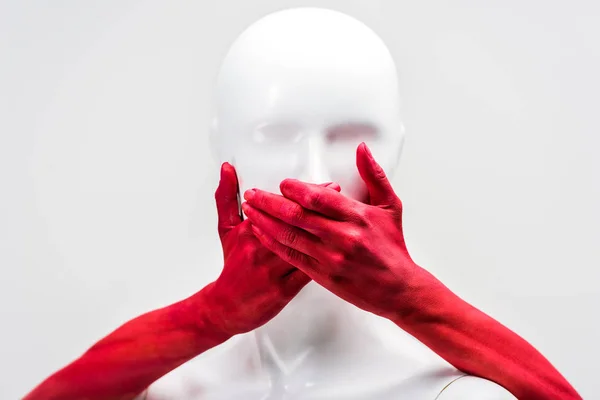 Cropped image of woman in red paint covering mannequin mouth with hands isolated on white — Stock Photo