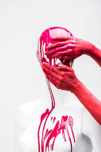 Abgeschnittenes Bild einer Frau in roter Farbe, die das Gesicht einer Schaufensterpuppe isoliert auf weißem Grund bedeckt — Stockfoto