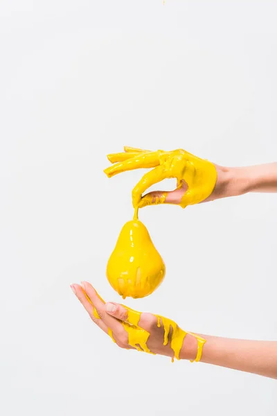 Cropped image of woman in yellow paint holding pear isolated on white — Stock Photo