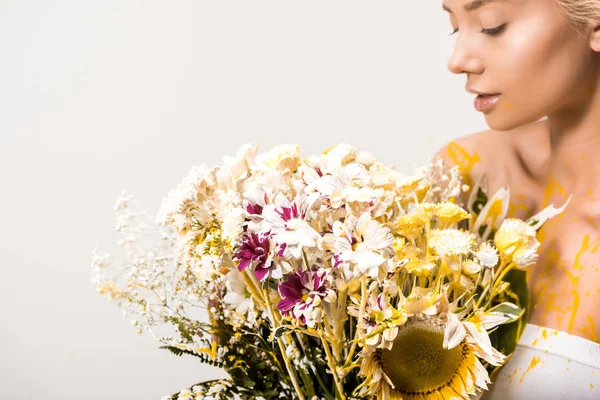 Jolie femme avec bouquet de fleurs et peinture jaune sur le corps isolé sur blanc — Photo de stock