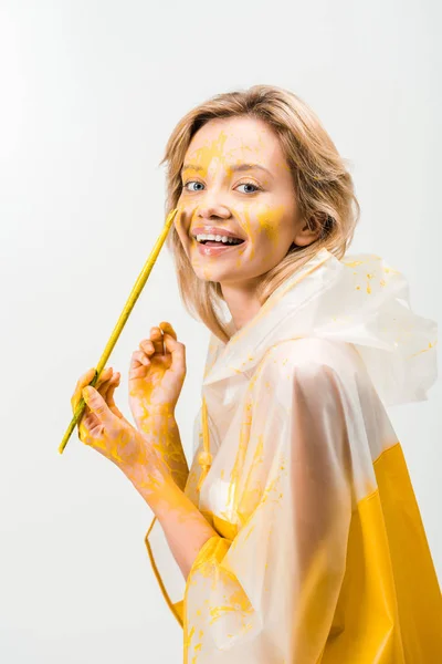 Sourire belle femme en imperméable peinture visage avec de la peinture jaune isolé sur blanc — Photo de stock