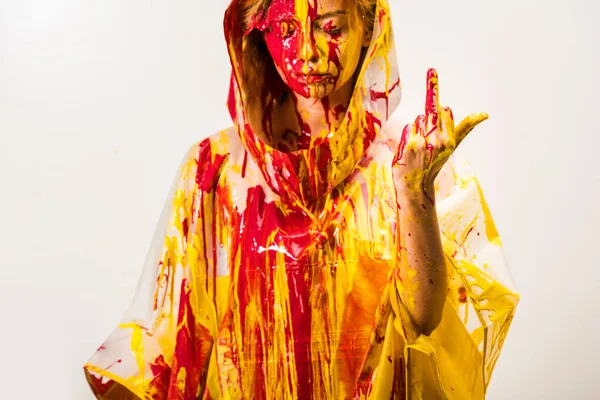 Donna in impermeabile dipinto con vernici gialle e rosse che mostrano dito medio isolato su bianco — Foto stock