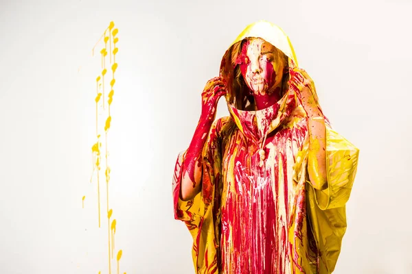 Belle femme en imperméable peint avec des peintures jaunes et rouges portant capuche isolée sur blanc — Photo de stock