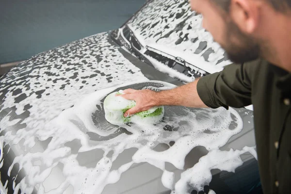 Abgeschnittenes Bild eines Mannes, der Auto in Waschanlage mit Lappen und Schaum reinigt — Stockfoto