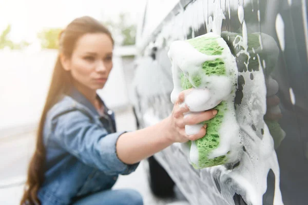 Mujer atractiva limpieza de coches en el lavado de coches con trapo y espuma - foto de stock