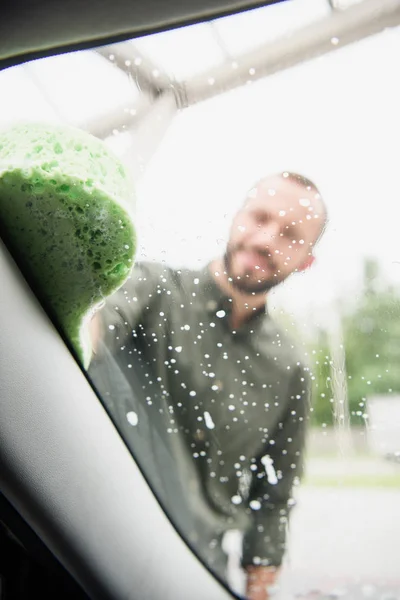 Mann putzt Autoscheibe mit Lappen und Seife in Waschanlage — Stockfoto