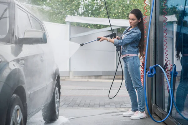 Beautiful woman cleaning car at car wash with high pressure water jet — Stock Photo