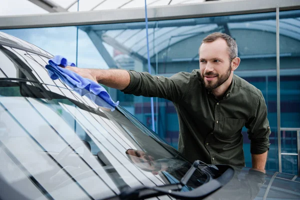 Bell'uomo che pulisce il finestrino dell'auto all'autolavaggio con straccio — Foto stock