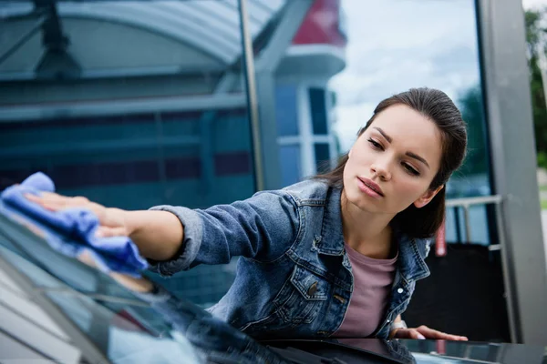 Schöne Frau putzt Auto in Waschanlage mit Lappen — Stockfoto