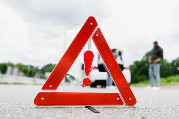 Homem e mulher de pé na estrada com sinal de parada vermelho em primeiro plano — Fotografia de Stock