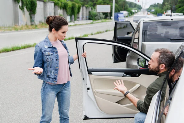 Conducenti maschi e femmine che litigano e gesticolano su strada dopo un incidente stradale — Foto stock