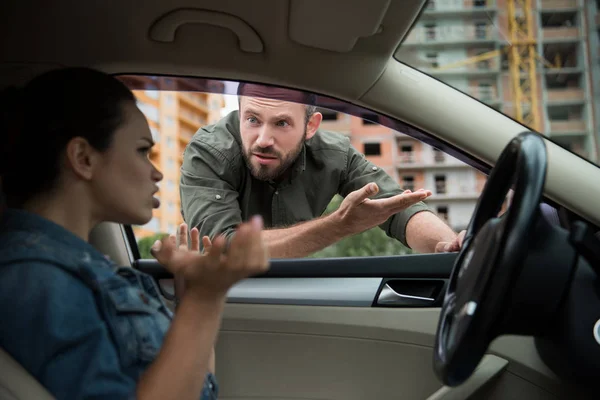 Hombre enojado haciendo un gesto al conductor a través de la ventana del coche - foto de stock