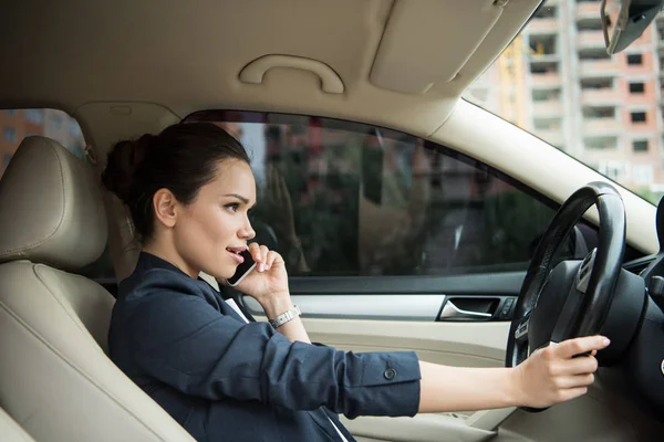 Side view of attractive woman using smartphone while driving car — Stock Photo