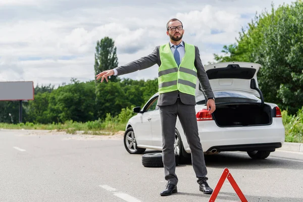 Schöner Geschäftsmann in hellgrüner Weste stoppt Auto auf der Straße — Stockfoto