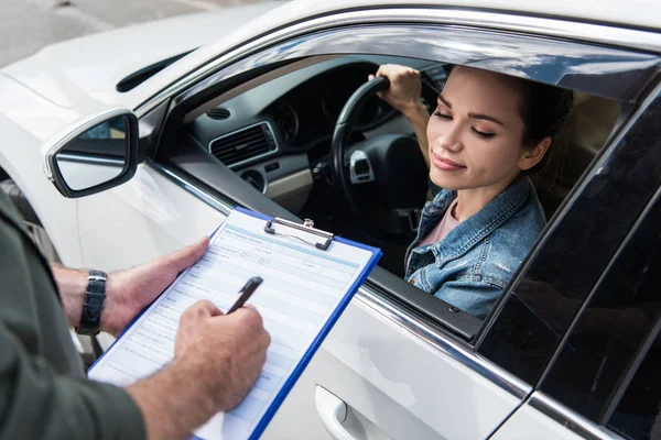 Imagem cortada do motorista esperando enquanto o homem escrevendo algo para o seguro de carro na estrada — Fotografia de Stock