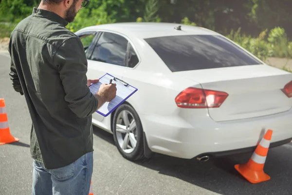 Imagem cortada do homem escrevendo algo para o seguro de carro na estrada — Fotografia de Stock