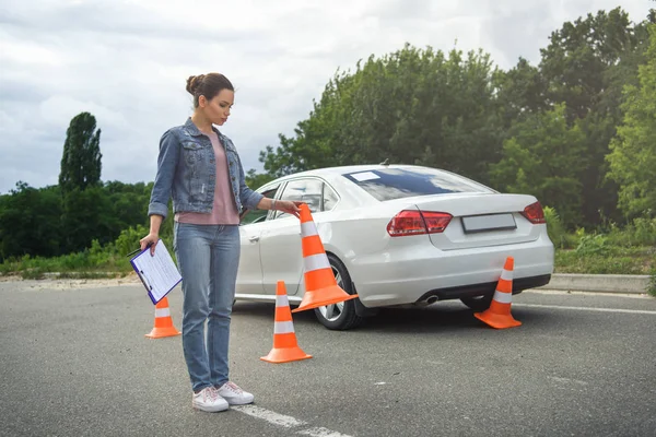 Motorista segurando seguro automóvel e colocando cones de tráfego na estrada — Fotografia de Stock