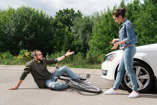 Driver and biker quarreling after car accident on road — Stock Photo