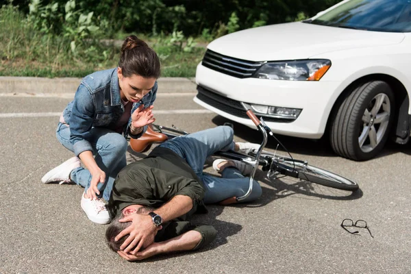 Conductor femenino ayudando a ciclista masculino después de accidente de coche en la carretera - foto de stock