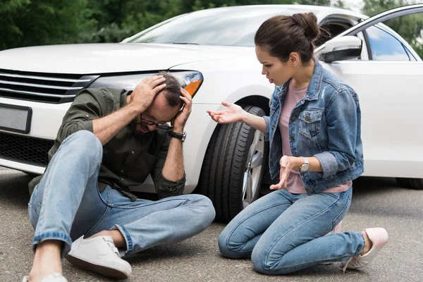 Conductor sentado cerca de hombre en la carretera después de accidente de coche - foto de stock