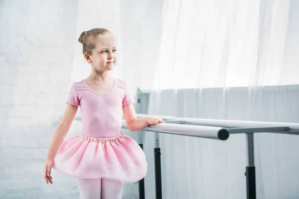 Красива дитина в рожевому підручнику практикує балет і дивиться в балетну школу — стокове фото