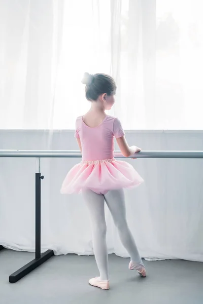 Вид сзади на маленького ребенка в розовой пачке, практикующего балет в балетной школе — стоковое фото